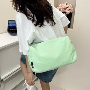 Détail d'un grand sac bandoulière vert menthe porté par un mannequin en intérieur