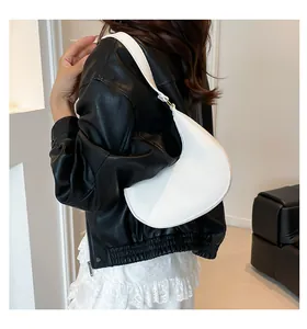 Close-up of a white crescent shoulder bag with lychee texture on a model wearing black