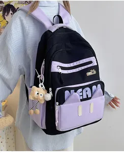 Detail of school backpack featuring black and purple panels with a cute monster plush toy charm