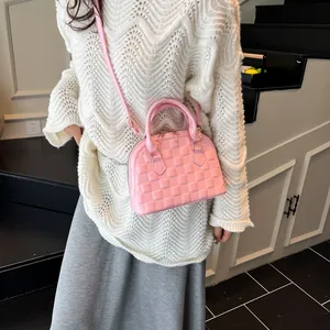 Detailed close-up of pink quilted shell bag with twin handles and adjustable strap
