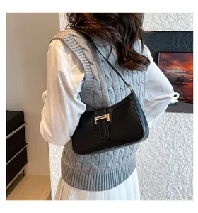 Detail of a black crescent underarm bag featuring a gold H-shaped metal buckle on smooth leather