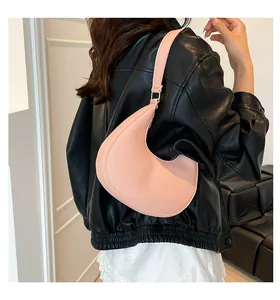 Detail of light pink crescent underarm bag with litchi grain texture and gold hardware