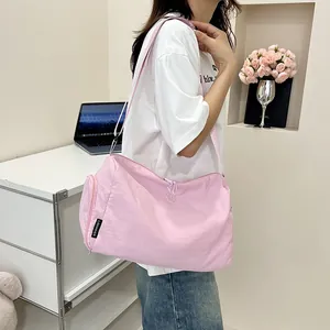 Détail du sac à bandoulière en nylon rose avec poche zippée latérale et étiquette