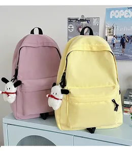 Pink and yellow nylon school backpacks with cute plush charms on a blue cabinet