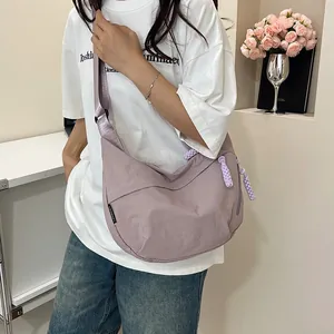 Dettaglio della borsa a mezzaluna in nylon lilla con tirazip intrecciato e tracolla