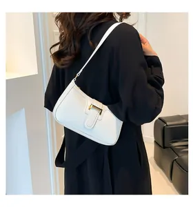 White minimalist crescent shoulder bag with golden metallic buckle worn by a model
