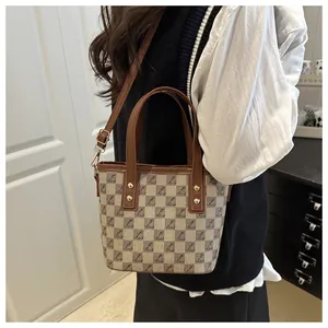Detail of checkered bucket bag with leather strap and golden hardware on a model
