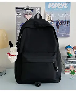 Detail of a black nylon backpack with front pocket and a white plush dog keychain charm