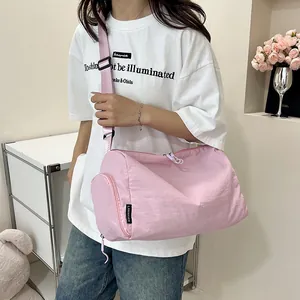 Détail du sac à bandoulière cylindrique rose en nylon avec fermeture éclair blanche