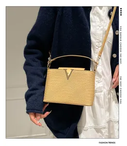 Detalle de bolso amarillo con textura, hebilla en V dorada y un diseño de tejido trenzado