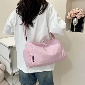 Détail du sac bandoulière cylindrique rose avec étiquette et zip en forme de cœur
