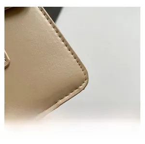Détail de la texture cuir crocodile beige avec coutures précises sur le sac à main