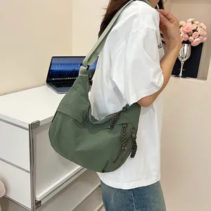 Dettaglio della borsa a tracolla in nylon verde scuro con cerniera intrecciata e cinghia
