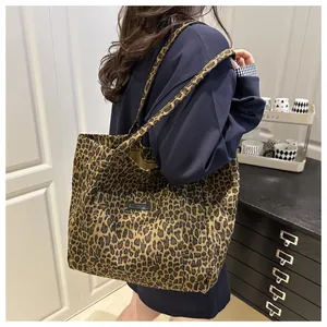 Detailansicht einer großen Canvas-Tasche mit Leopardenmuster, getragen von einem Modell