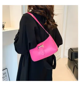 Close-up of bright pink leather crescent bag featuring a prominent gold H-shaped buckle