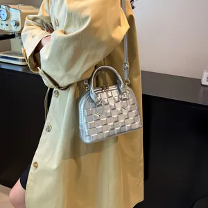 Detail of silver metallic shell bag showing quilted texture and dual handles