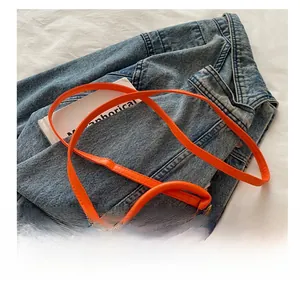 Detail view of orange PU leather mini bag showing the adjustable shoulder strap and knot buckle