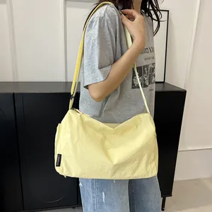 Détail du sac bandoulière en nylon jaune clair avec sangle large et étiquette latérale