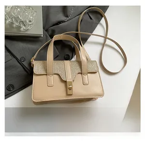 Détail du sac beige motif crocodile avec fermoir doré posé à côté d'un smartphone