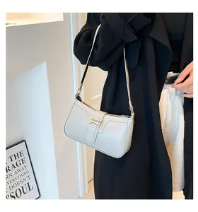 Detail of a beige crescent shoulder bag with a gold H-shaped metallic buckle detail