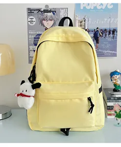 Detail of a yellow nylon backpack with a zipper pocket and white puppy plush keychain