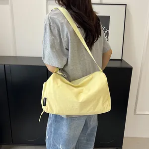 Détail du sac bandoulière en nylon jaune clair avec étiquette de marque et bandoulière