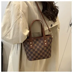 Close-up of vintage brown plaid tote bag with letter prints and gold rivet details