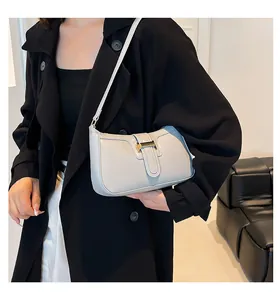 Detail of light grey leather crescent bag with gold buckle on a model's shoulder