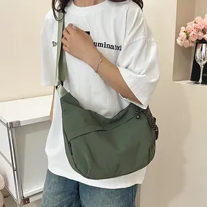 Dettaglio della borsa a mezzaluna in nylon verde scuro con tracolla e ciondolo intrecciato