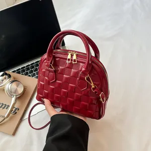 Detail of burgundy shell bag with checkered embossed patent leather and gold hardware