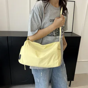Gros plan d'un sac bandoulière en nylon jaune clair avec étiquette latérale et fermeture
