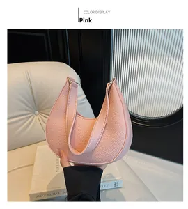 Detailed shot of pink pebble leather crescent handbag with elegant shoulder strap handle