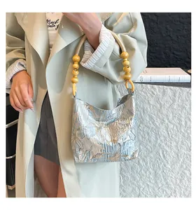Dettaglio del tessuto jacquard floreale e manico in perle di legno vintage della borsa