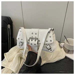 Close-up of white patent leather shoulder bag featuring silver metal studs and buckles