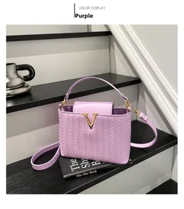Primer plano del bolso tejido púrpura con logo V dorado y textura de cuero de lujo