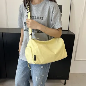 Gros plan d'un sac cylindrique en nylon jaune pâle avec bandoulière réglable sur le modèle