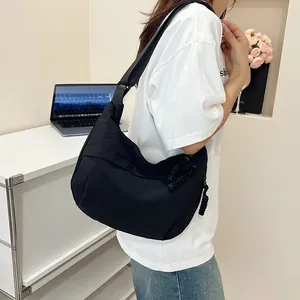Dettaglio di una borsa a tracolla a mezzaluna in nylon nero con tracolla larga e zip