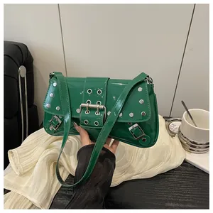 Close-up of emerald green patent leather bag with metal rivets and punk Y2K buckle detail