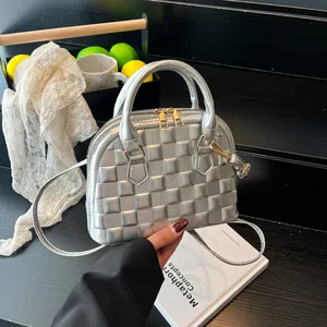 Silver shell-shaped handbag with embossed plaid texture and adjustable strap on a display