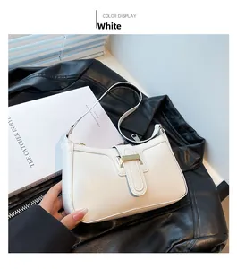Detailed view of the white crescent underarm bag featuring a metallic gold buckle closure
