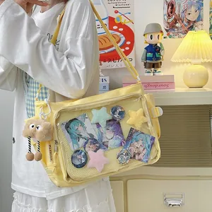 Yellow canvas messenger ita bag with clear pocket and cute plush monster charm strap