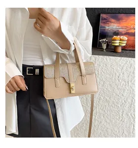 Détail d'un sac à main beige motif crocodile avec rabat pailleté et fermoir doré