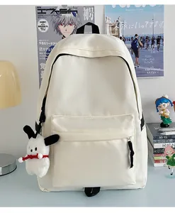 Detail of cream white nylon backpack with large front pocket and cute dog plush pendant