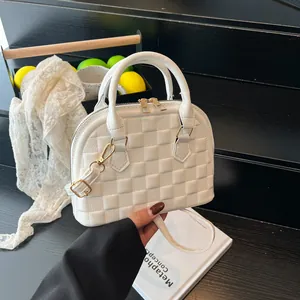 Detail of white shell handbag featuring checkered pattern and golden zipper on wood