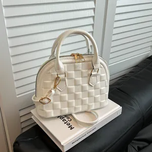 Detailed view of white glossy quilted shell bag with gold zippers and metal hardware