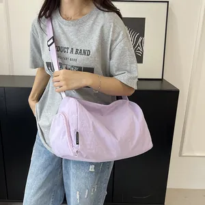 Détail du sac bandoulière en nylon lilas avec poche zippée et étiquette de marque