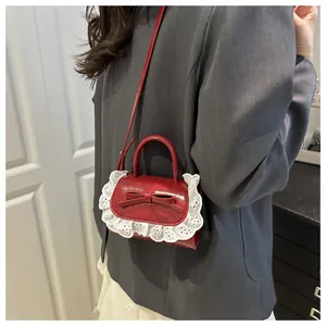 Détail d'un mini sac à main rouge avec bordure en dentelle blanche et un nœud décoratif