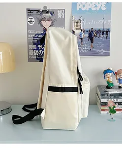 Detailed side view of a white nylon backpack with adjustable black straps on a desk