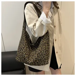 Detailed view of leopard print canvas hobo bag texture and drape on model's shoulder