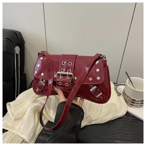 Detail of red glossy punk shoulder bag with silver metal studs and buckles